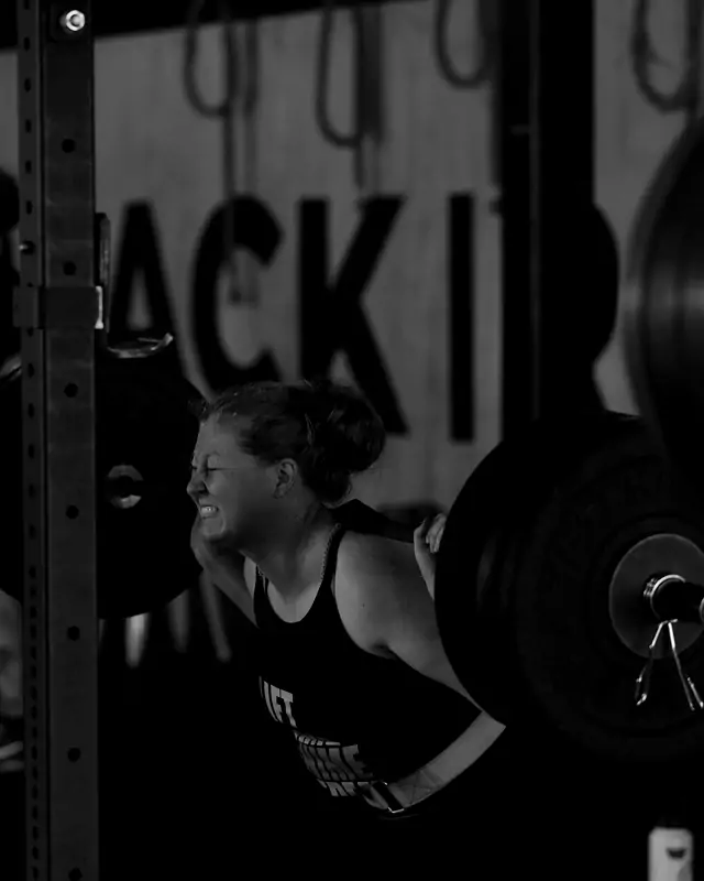 A member under the bar in a back squat